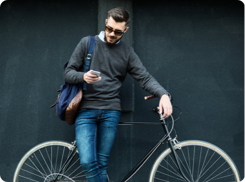 Man standing with a bike, using a mobile device