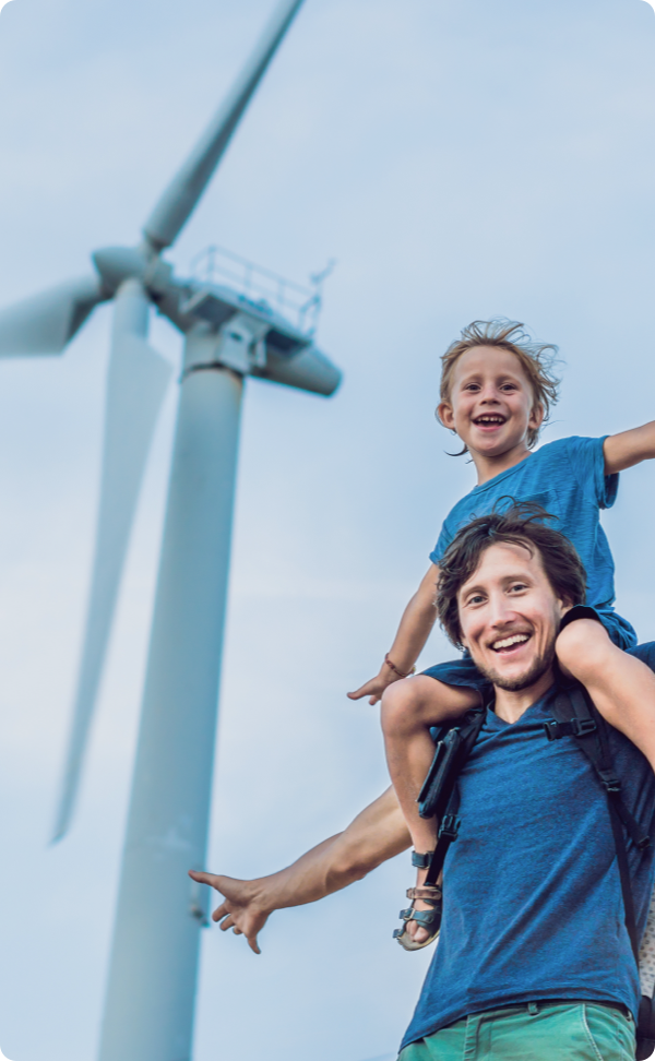 Portrait of father holding son on shoulders next to windmill