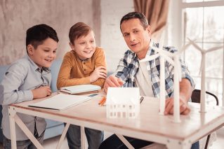 Portrait of man showing windmill figurines to children at table