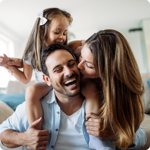 Father playing with daughter while his wife kisses him on cheek