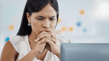 Woman looks at computer with concern